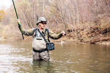 Fisherman holding a grayling caught in river