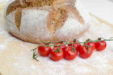 Home Baked Natural Bread With Fresh Cherry Tomatoes On Wooden Table Closeup