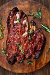 Grilled pork ribs on wooden board, top view