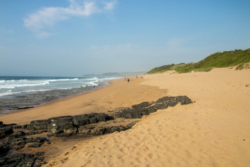 Rocks on Sandy Beach and Blue Coastal Skyline