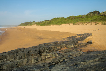 Rocks on Sandy Beach and Blue Coastal Skyline