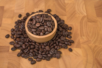 Coffee beans in wooden bowl on wooden background