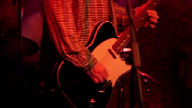 Rock musician plays the final chords on his electric guitar at the end of the alternative rock show on stage