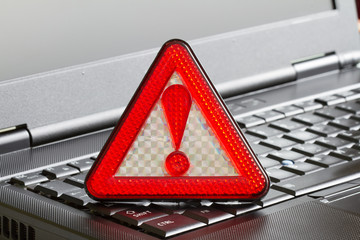 Caution sign on black laptop computer virus detected alert hacking piracy concept
