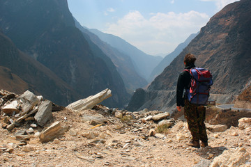 Lonely hiker looks at one of the deepest ravines of the world, Tiger Leaping Gorge in Yunnan,...