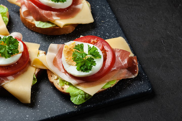 Delicious sandwich with prosciutto ham, cheese, tomato and egg