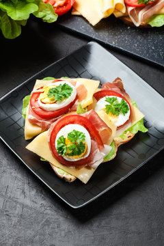 Delicious sandwich with prosciutto ham, cheese, tomato and egg