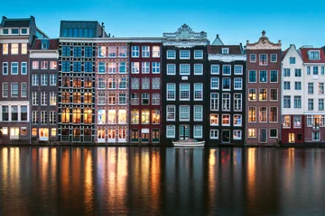 Papier Peint photo Amsterdam Famous old buildings with lights in Amsterdam reflecting in water as blue hour