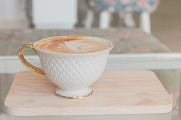 White cup of coffee on wooden table in the coffee shop.