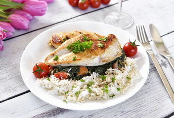 Grilled chicken breast with vegetables, rice and cherry tomatoes. Healthy eating scene, grilled chicken on a white, wooden table with pink tulips.
