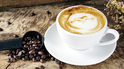 Cappuccino Coffee. A cup of latte, cappuccino or espresso coffee with milk put on a wood table with dark roasting coffee beans. Drawing the foam milk on top.
