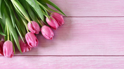 Flower bouquet of pink tulips on a wooden table or wooden planks. Spring background with copy space and pink spring flowers.