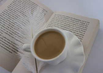 White cup with coffee with feather on white background