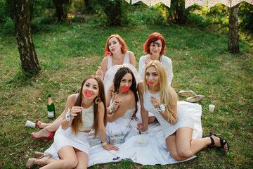 Girls wearing on white dresses having fun on hen party.