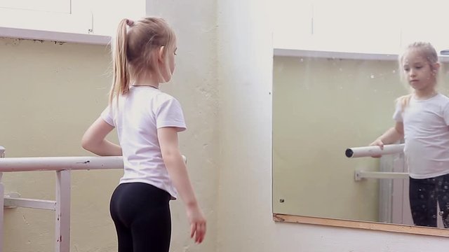 The young girl dances in a ballet tutu in the hall