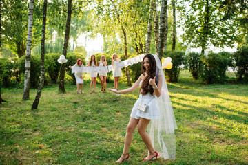 Girls wearing on white dresses having fun on hen party.