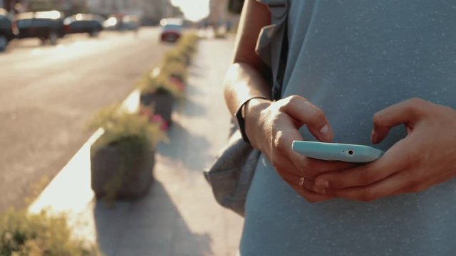 Woman using a mobile phone in the city in summer, close-up