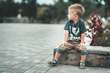 Little baby boy in fashionable clothing have fun outdoors