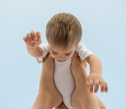 Father holding baby son on his legs in air