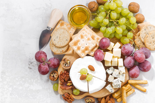 camembert, grapes and snacks on a white background, top view