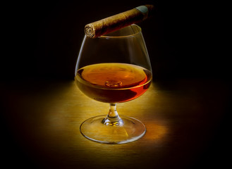A glass of whiskey with a cigar