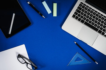 view of the blue desk with a computer tablet and paper