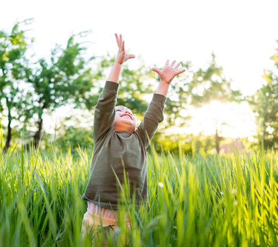 Little child in grass with hands up
