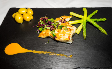 Fischfilet mit Spargel und Kartoffeln auf einer Schieferplatte angerichtet