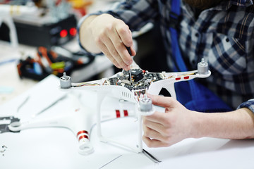 Closeup shot of male hands opening quadrocopter drone and unscrewing the main circuit board working...