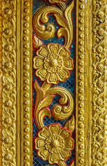Fototapeta na wymiar Vintage old golden floral sculpture on wall. The Thai design patterns are made from concrete and stucco.
