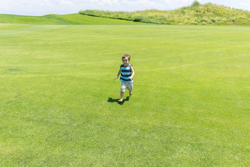 Little kid running on green meadow