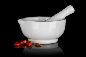 White ceramic mortar with dried chili peppers isolated on black