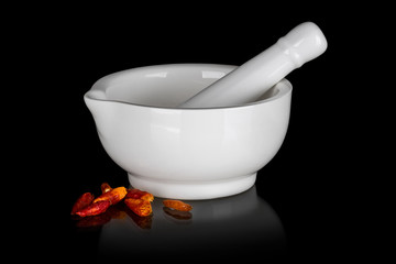 White ceramic mortar with dried chili peppers isolated on black