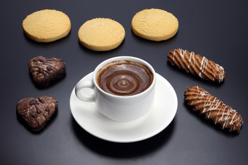 white cup of black coffee with biscuits on a dark background