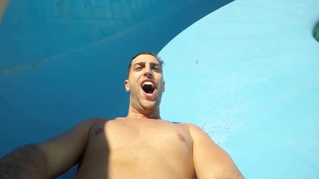 Man having fun and sliding down in a water slide
