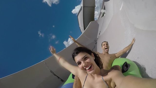 Couple having fun and sliding down in a water slide