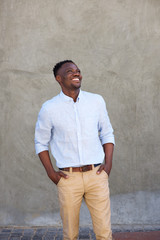 modern young black man smiling with hands in pockets