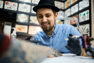 Happy young tattoo artist at work