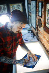 Obraz na płótnie Canvas Creative man in tattoo workshop drawing adornment