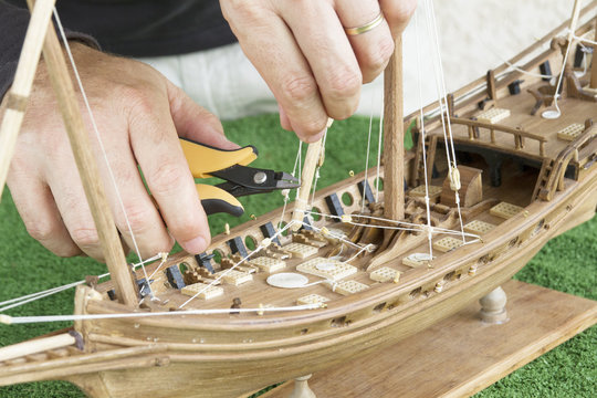 Mod&eacute;liste travaillant sur une maquette de bateau en bois