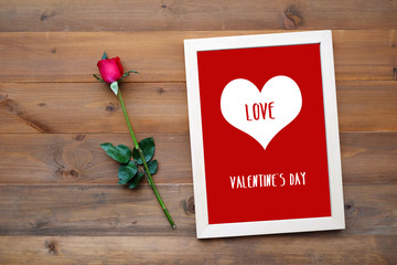 Happy valentine's day card and red rose on wood background