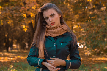 Fototapeta na wymiar serious young girl in a black jacket stands in autumn Park
