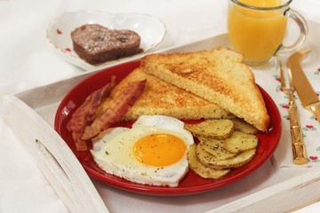 Breakfast in bed with egg heart Bacon bread toast roasted potatoes and orange juice served in wooden tray for Valentine's day