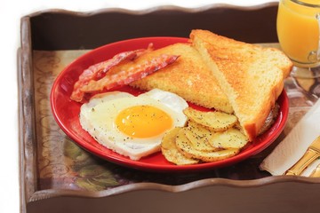 Breakfast in bed with egg heart Bacon bread toast roasted potatoes and orange juice served in wooden tray for Valentine's day