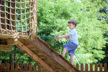 Little toddler boy kid having fun at a wooden playground outdoor