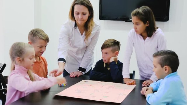 Children making move on pre-marked surface of board game at classroom