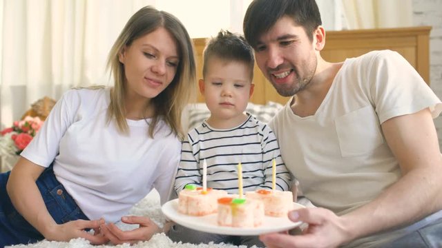Smiling family celebrating their son birthday together before blowing candles on cake