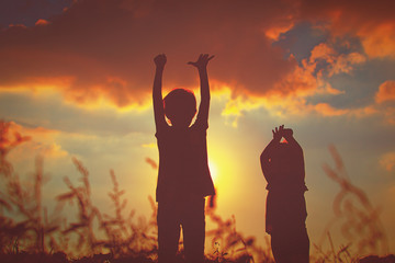 little boy and girl silhouettes play at sunset