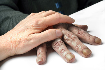 mano che protegge una mano di anziano povero 