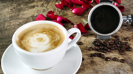 Cappuccino coffee with roses. A cup of latte, cappuccino or espresso coffee with milk put on a wood table with dark roasting coffee beans. Drawing the foam milk on top.